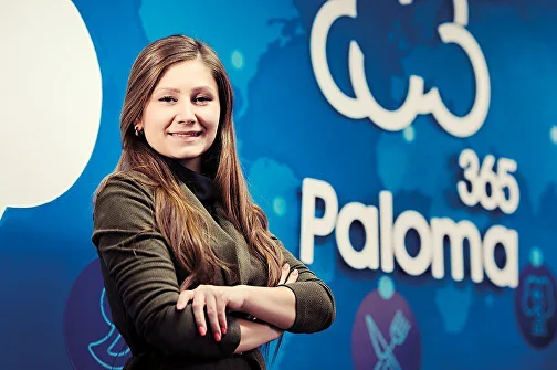 Сотрудница Paloma365 на фоне логотипа компании